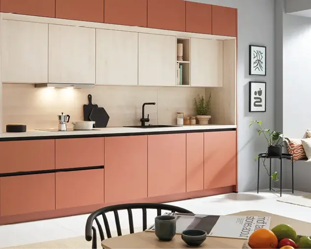 Moderne Einbauküche mit terrakottafarbenen Fronten, hellen Holzoberschränken und schwarzer Arbeitsplatte. Zeitloses Küchendesign mit klaren Linien, integrierten Geräten und stilvoller Beleuchtung in offenem Wohnraum.